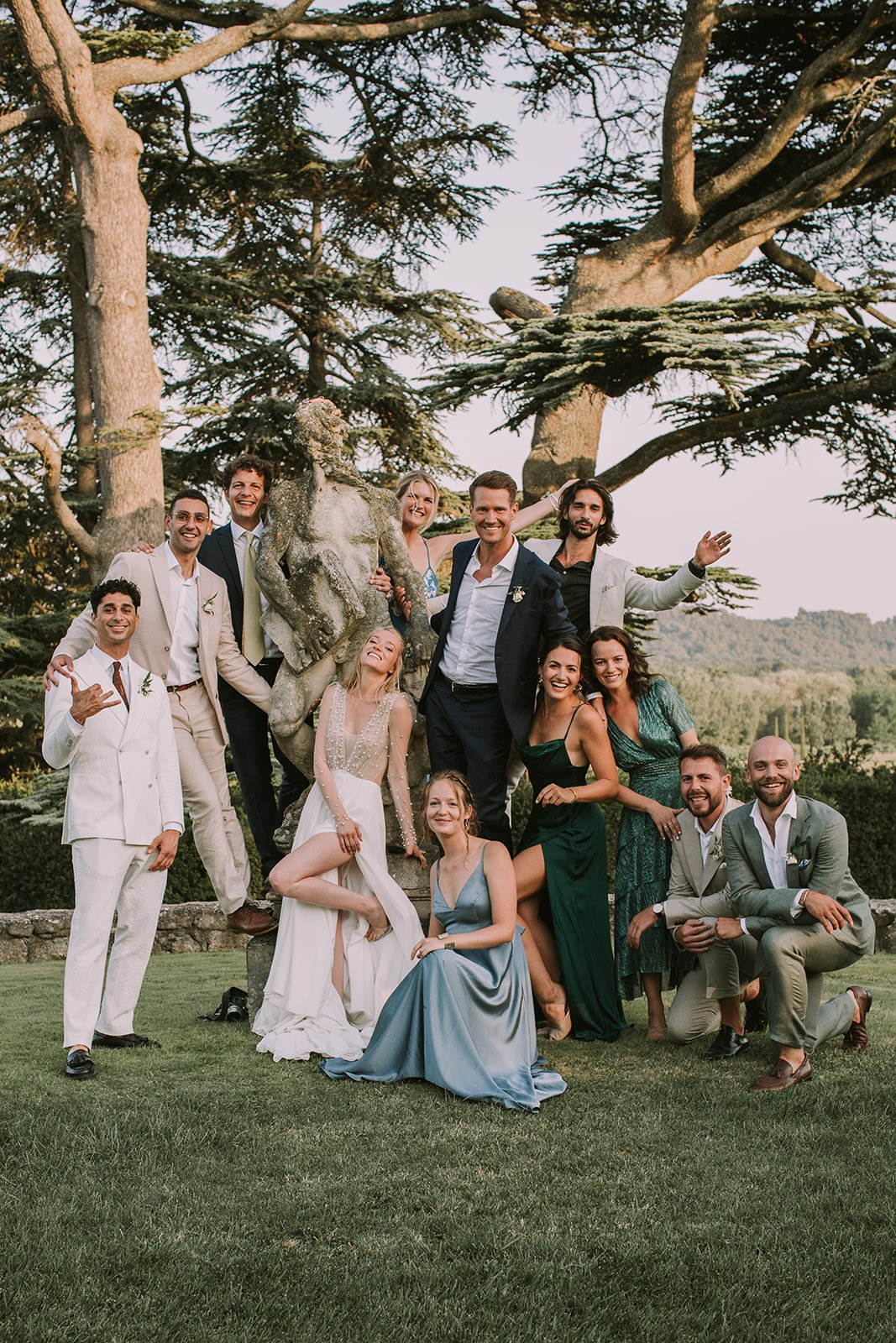 Photo de groupe au Château Sannes, mariés et invités autour d'une statue lors d'une réception wedding planner en Provence